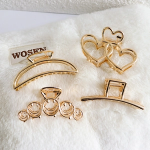 Set of four gold metal hair claws featuring heart, smiley, and geometric cutout designs
