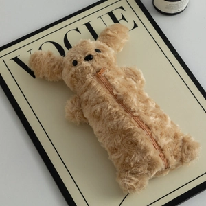 Gros plan d'une trousse chien en peluche marron avec fermeture éclair sur fond Vogue
