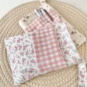Close-up of floral and plaid nurse pouch organizers on a woven mat with fabric texture