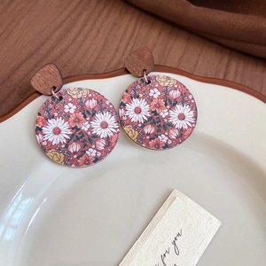 Gros plan de boucles d'oreilles rondes en bois vintage aux motifs de marguerites