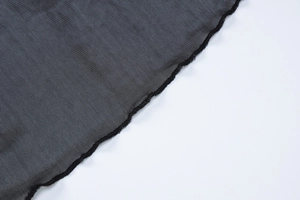 Detail of sheer black mesh fabric featuring delicate ruffle edges and fine texture