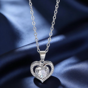 Detailed macro view of silver heart pendant with sparkling pavé zircons on blue silk