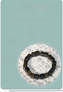 Detail of dark brown agarwood bracelet with square beads and gold spacers on paper