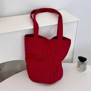 Detalle de la textura acolchada vertical roja en este bolso de hombro minimalista