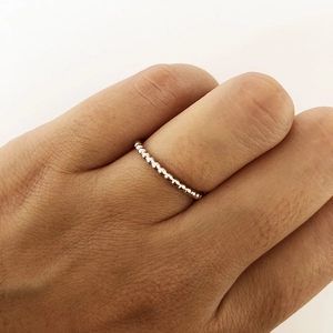 Detailed close-up of a silver beaded stacking ring showing smooth metallic bead texture