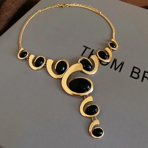 Detail view of a gold oval necklace with black stones in a professional jewelry box