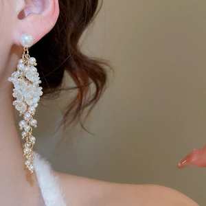 Detail of long floral tassel earrings with pearls and white petals on model