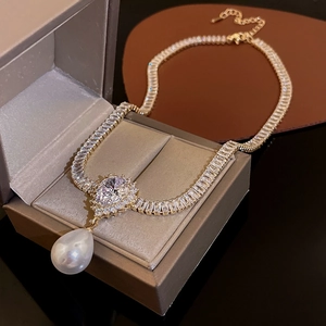 Close-up of gold plated pearl and teardrop zircon necklace displayed on a jewelry box