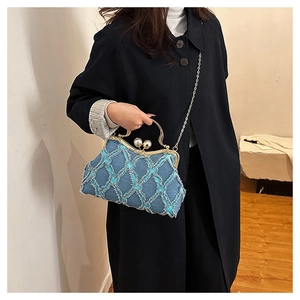 Close-up of quilted blue denim shell bag with large pearl clasps and gold chain strap