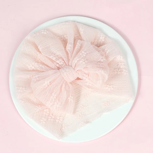 Close-up of baby lace turban hat in light pink with a large decorative mesh bow detail