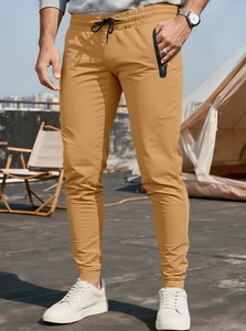 Outdoor close-up of men's yellow fitness joggers with drawstring and zipper pockets