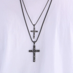 Detail of double-layered punk cross pendant with textured box chain in gunmetal finish