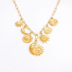 Detail of golden paperclip chain necklace with sun and moon pendants on white background