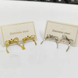 Detail of bow-shaped stainless steel stud earrings in polished gold and silver finish