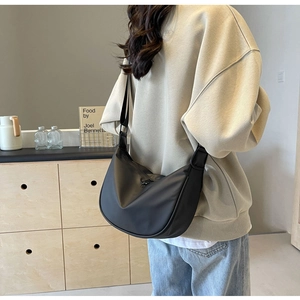 Detailed view of black matte dumpling bag with adjustable strap worn on model back