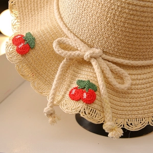 Kids straw sun hat in beige featuring red cherry embroidery and a decorative rope bow