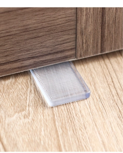 Close-up of transparent wedge shims leveling a dark wooden furniture leg on wood floor