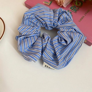 Detailed view of a blue and white striped fabric scrunchie with a woven brand tag