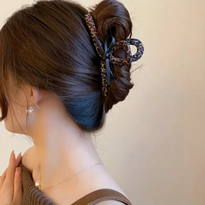 Elegant leopard print hair claw clip demonstrated on model with chic updo hairstyle