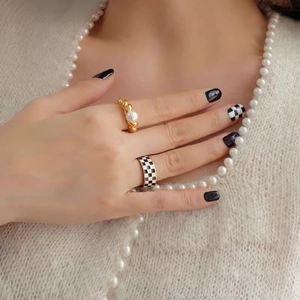 Twisted gold ring with freshwater pearl and checkered enamel ring set on a model hand