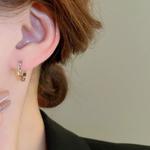 Macro shot of silver metal hoop earrings with irregular textured wave surface for women