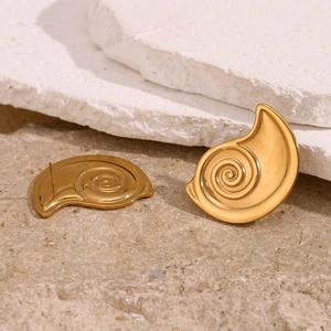 Detail view of 18K gold plated spiral conch stud earrings on minimalist stone texture