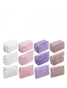 Close-up of plush checkerboard cosmetic bags with star zipper pulls in pastel colors