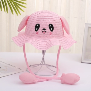 Detailed view of kids pink straw hat with movable ears and cartoon embroidery on a stand