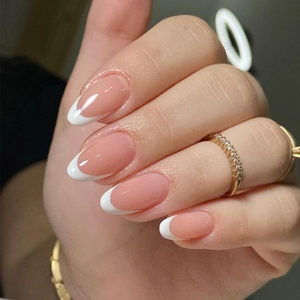 Close-up of elegant oval press-on nails with nude pink base and white French tips