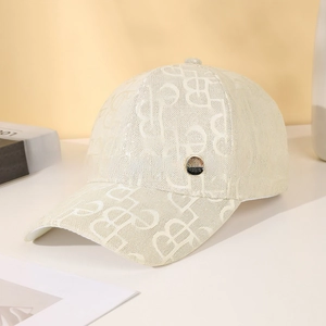 Detail of beige jacquard baseball cap with monogram pattern and metal emblem