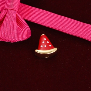 Macro detail of red Santa hat charm bead for DIY bracelets with festive gold trim