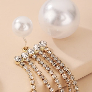 Macro shot of sparkling rhinestone fringe earrings with elegant white pearls on gold base