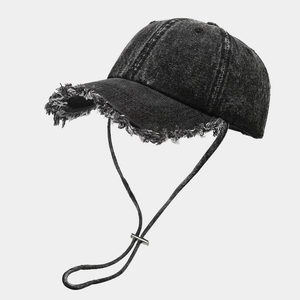 Dettaglio dei bordi sfilacciati sul cappello denim vintage con cordino antivento