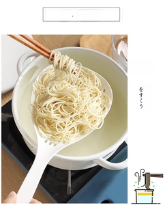 Detail of white long-handle noodle strainer scooping fine noodles from a pot