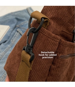 Detail of detachable black D-ring and metal hook on brown corduroy shoulder bag