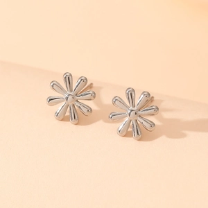 Detail of silver flower stud earrings with minimalist design on soft warm background