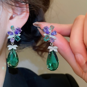 Close-up of luxury water drop earrings with purple flower and green gemstone