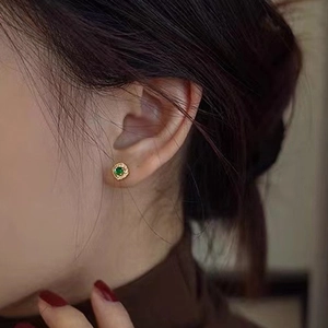 Close-up of a vintage S925 silver stud earring with emerald green stone and small diamonds