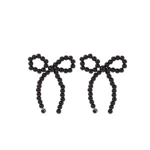Close-up of black beaded bow earrings with silver needles and elegant pearl-like beads