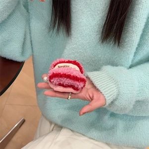 Close-up of pink and red plush knit earphone case with pearl charm held in hand