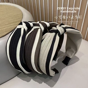 Detail of three knotted striped headbands in black, coffee, and beige ribbed fabric
