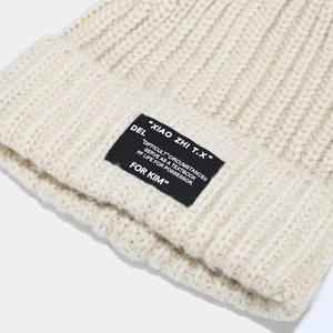 Macro-opname van een beige geribbelde gebreide muts met een zwart geweven textiellabel