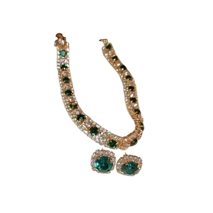 Luxurious gold geometric jewelry set with emerald gemstones and crystals on white background