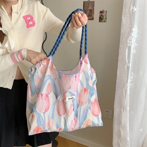 Detailed close-up of a large floral tote bag featuring tulip print and blue woven rope handles