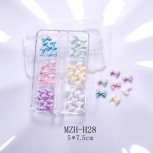 Close-up of glittery resin bow nail art charms in a 6-grid transparent organizer box