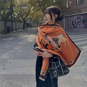 Detailaufnahme eines orangefarbenen Winterschals mit elegantem Kutschenmuster