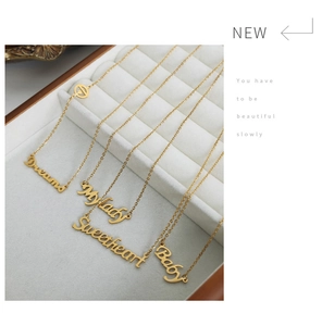 Dettaglio di quattro collane placcate in oro con ciondoli Dreams e Baby su velluto bianco