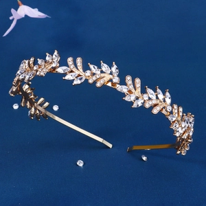 Elegant gold alloy headband with leaf design and sparkling rhinestones on blue background