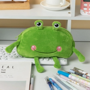 Funny green frog plush pencil case with long limbs placed on a white desk keyboard