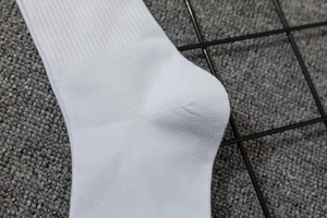 Detailed close-up of white knitted socks showing rib knit texture and reinforced heel